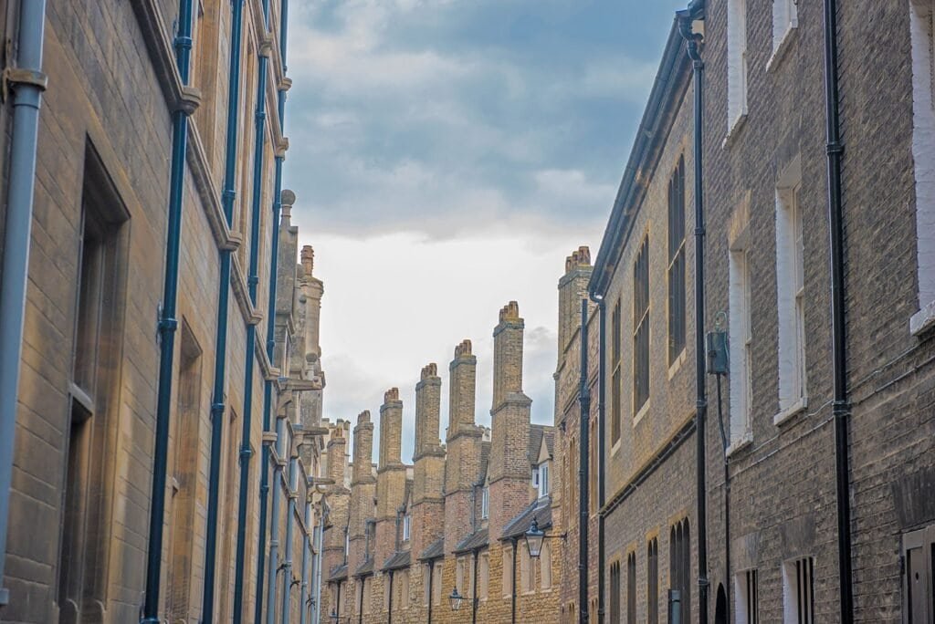 Charming historic street in Cambridge with traditional architecture and numerous chimneys.