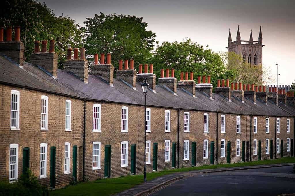 Charming historic row houses in Cambridge with iconic chimney pots and a view of the cathedral tower.